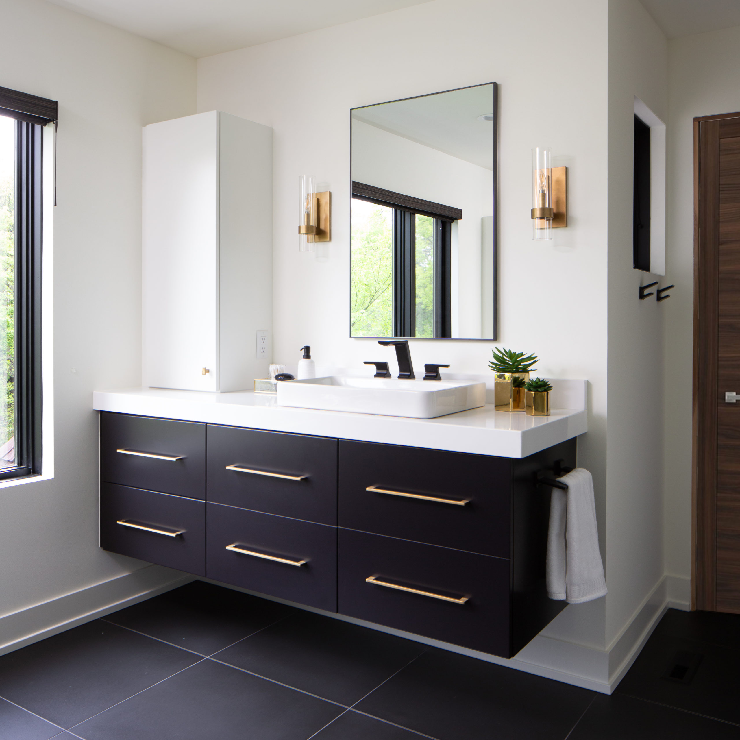 A bathroom with black cabinets and a window, showcasing our portfolio.