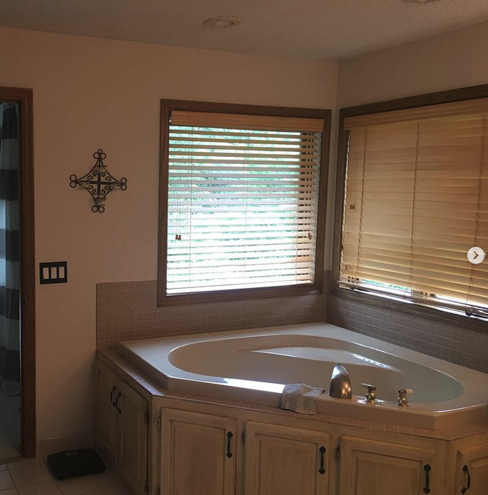 A bathroom with a jacuzzi tub and blinds showcasing its luxury features in our portfolio.
