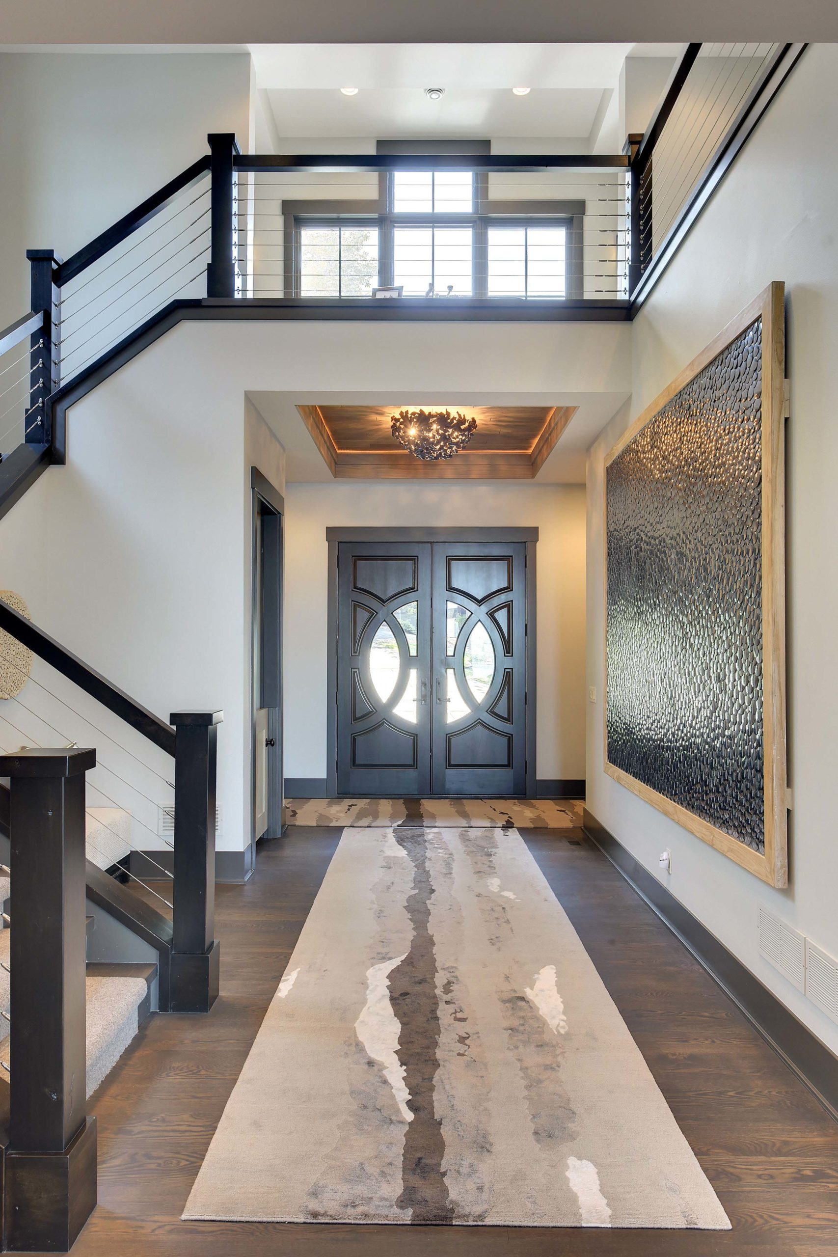 A modern entryway with a stylish staircase, adorned with a luxurious rug.