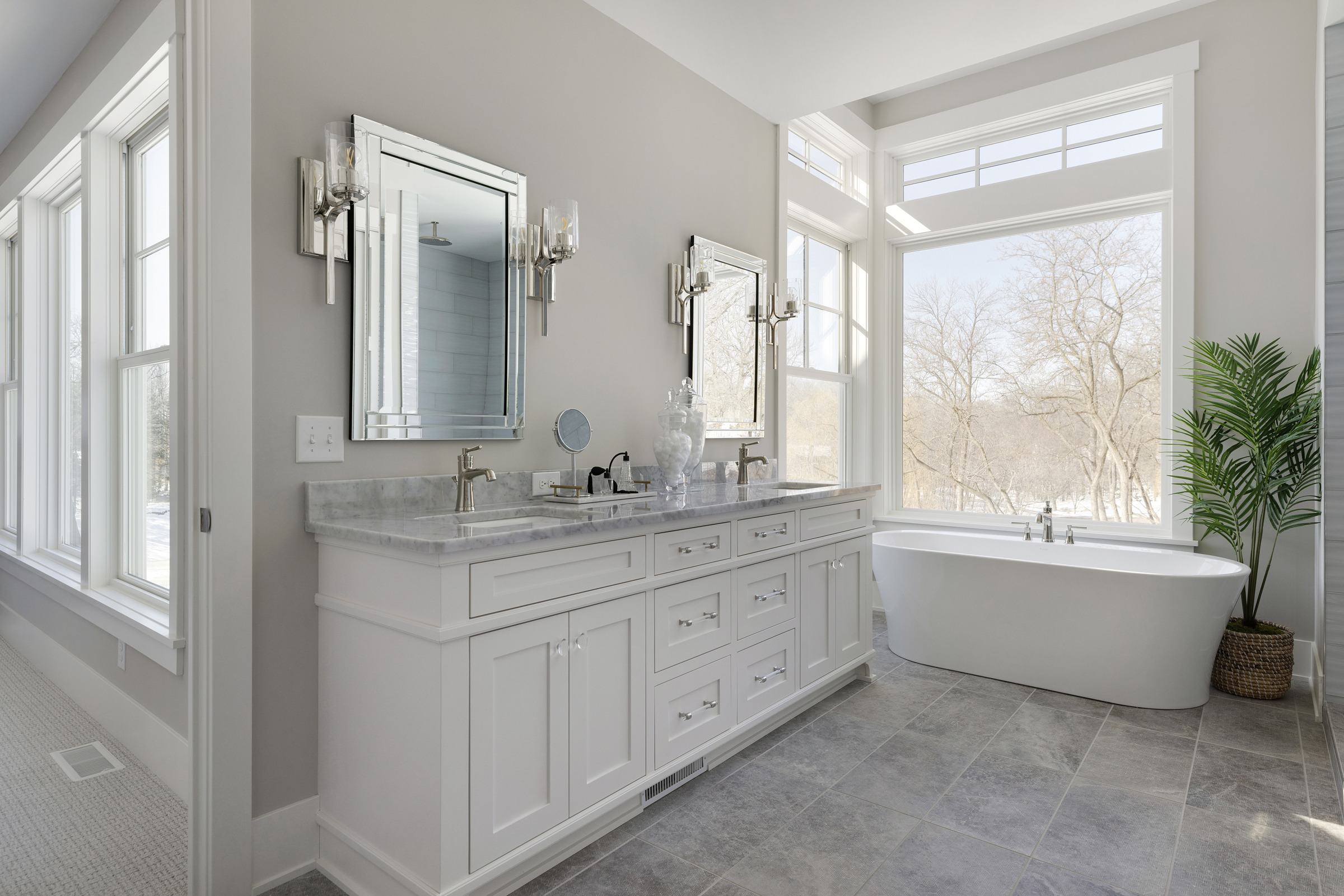 Master bathroom suite with white cabinets, a white soaker tub, and picture windows
