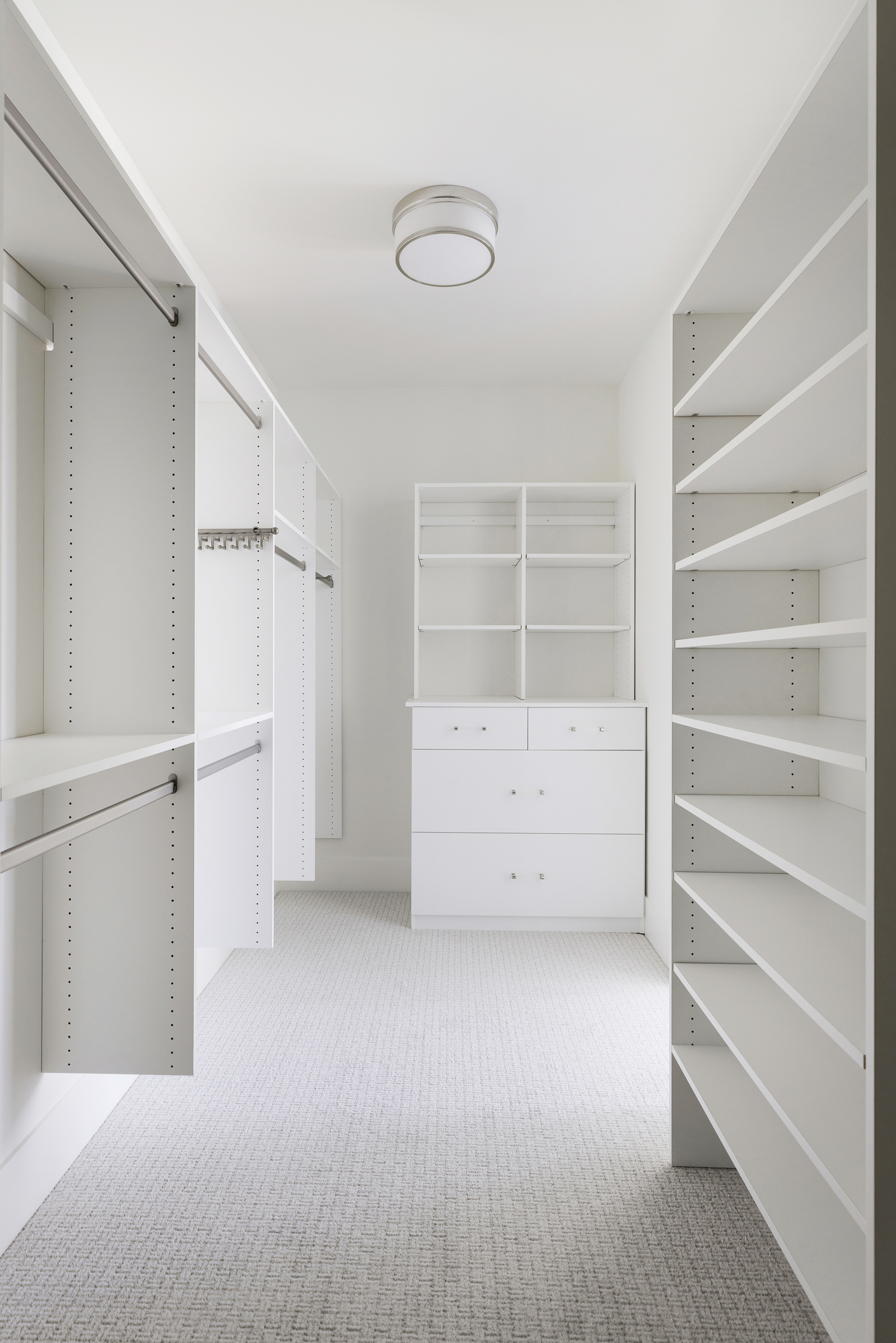 looking into the master bedroom closet with custom built in shelving and hanging rods