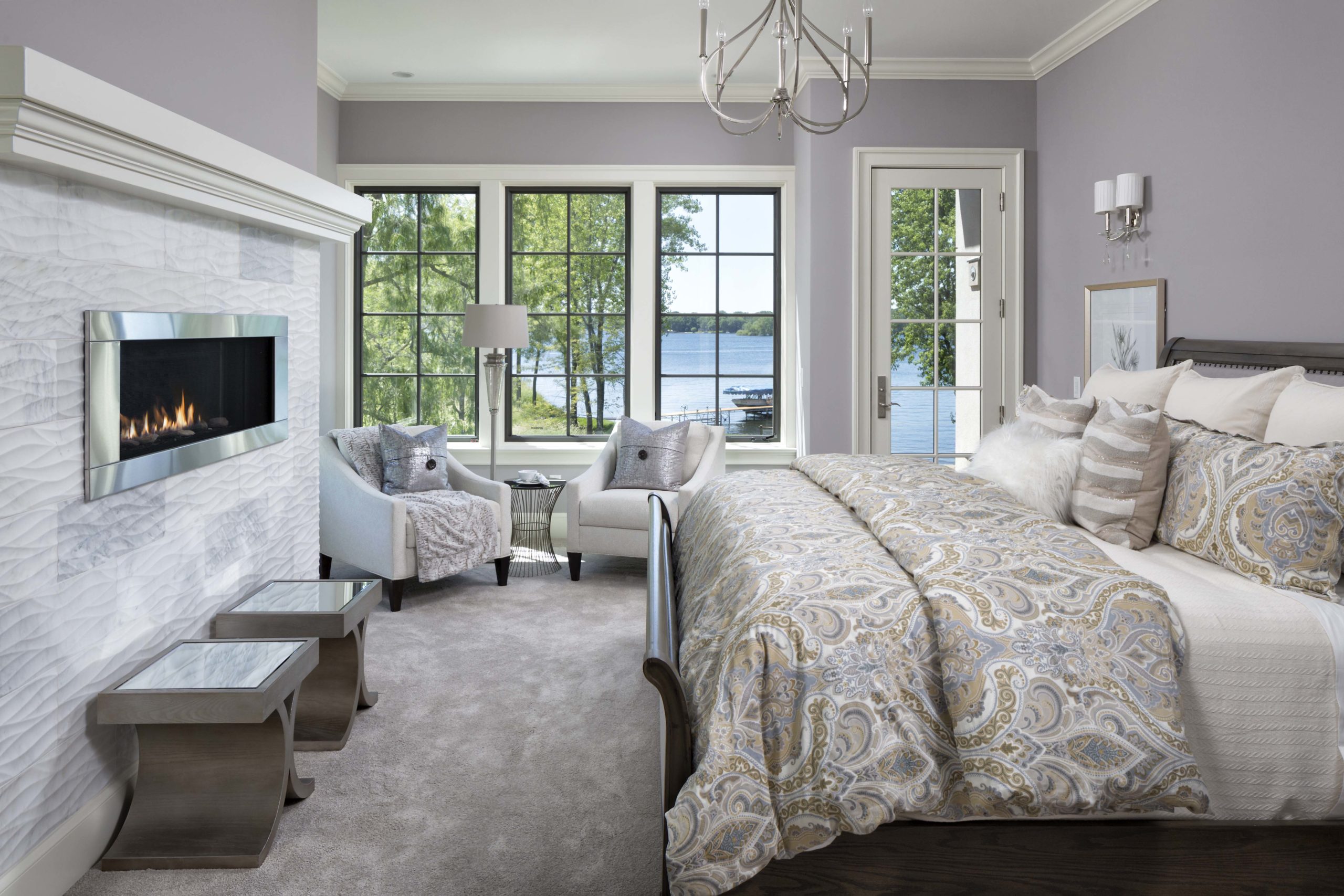 master bedroom with light grey walls and a fireplace across from a king sized bed