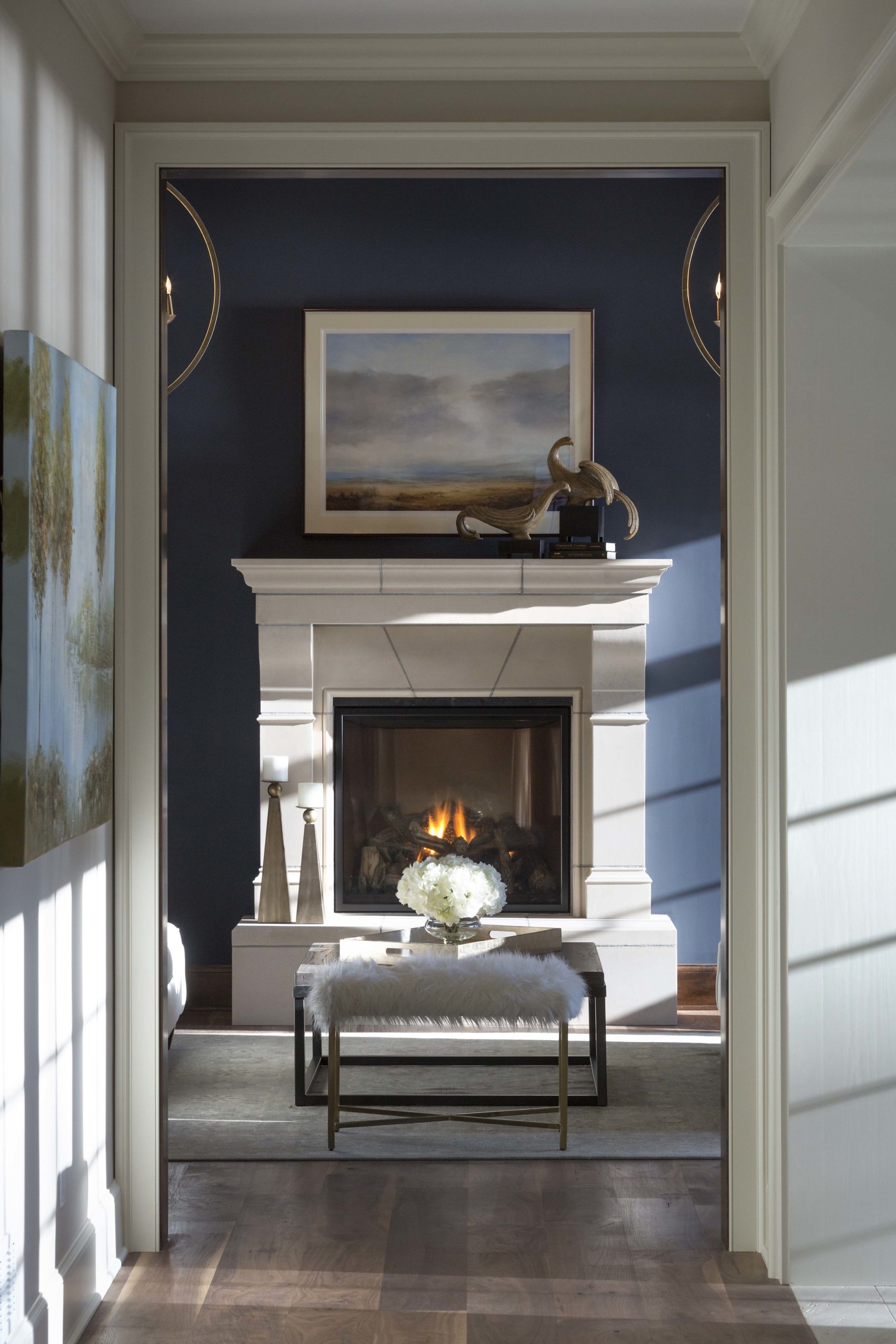 looking through a doorway into the living room with a white fireplace and dark blue walls