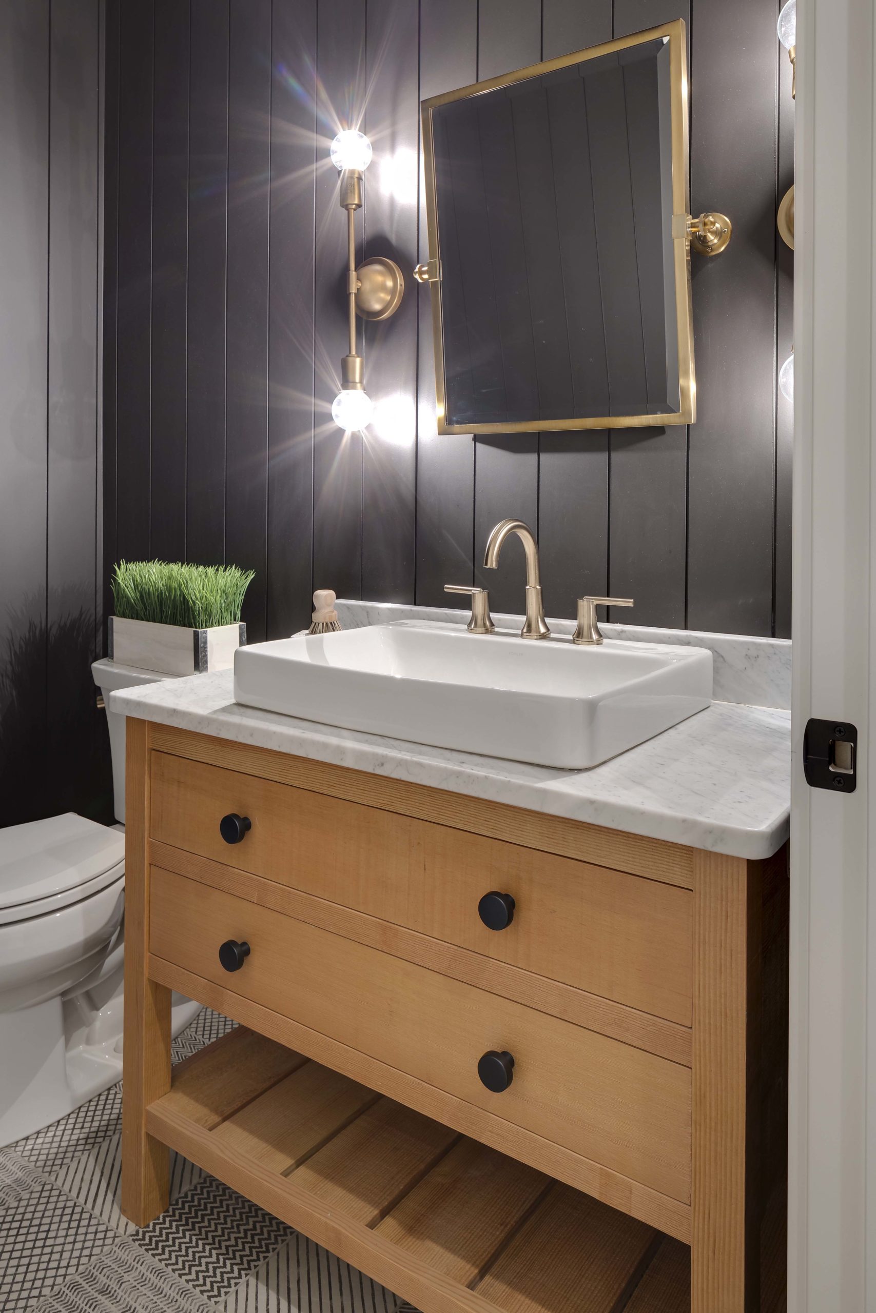 A black and gold bathroom with a sink and mirror in Reverence.