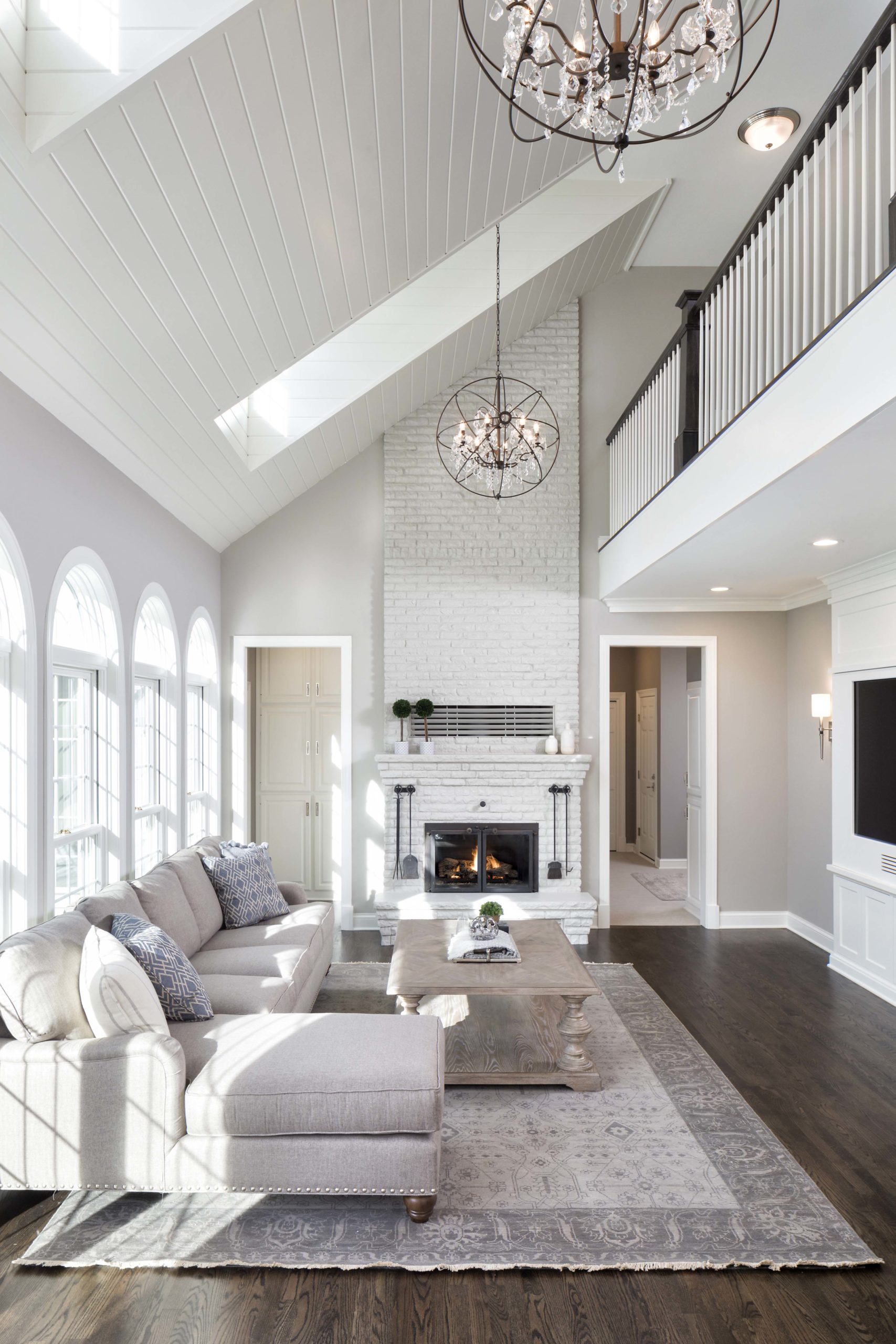 living room with two story ceilings, a sectional couch on the left, and a white brick fireplace on the back wall