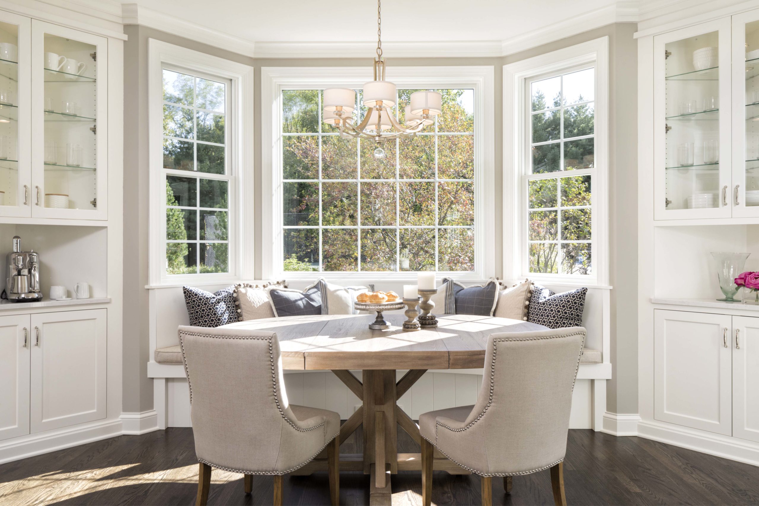 breakfast nook in kitchen with white bench, accent pillows, and tan chairs around the table