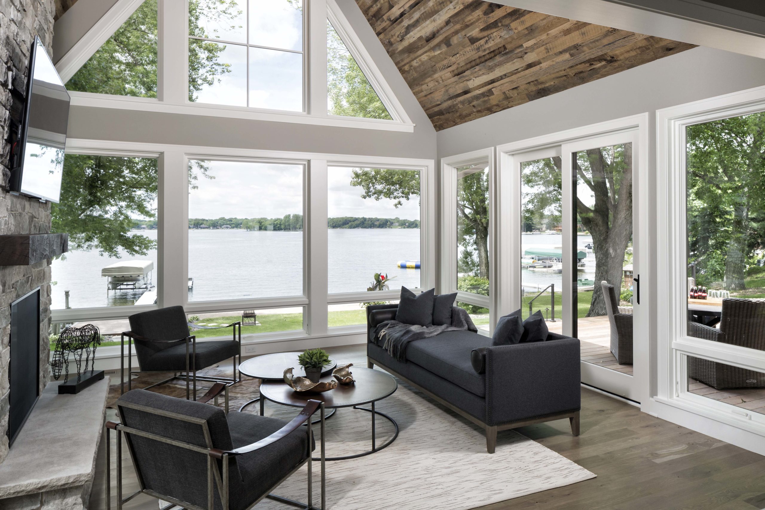 four season porch with floor to ceiling windows on all sides and black furniture