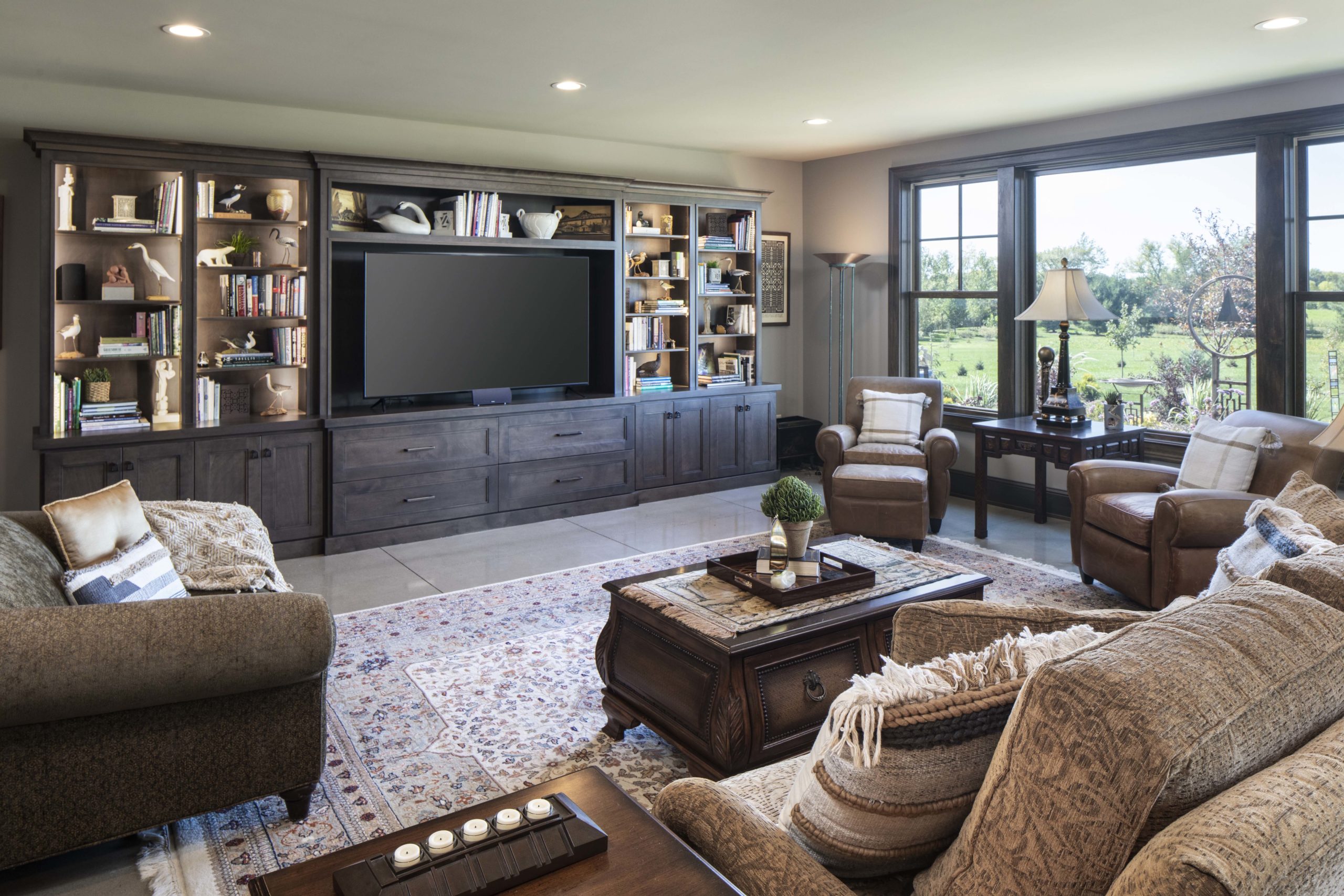 lower level living room with dark brown furniture and dark wood built in cabinets around the tv