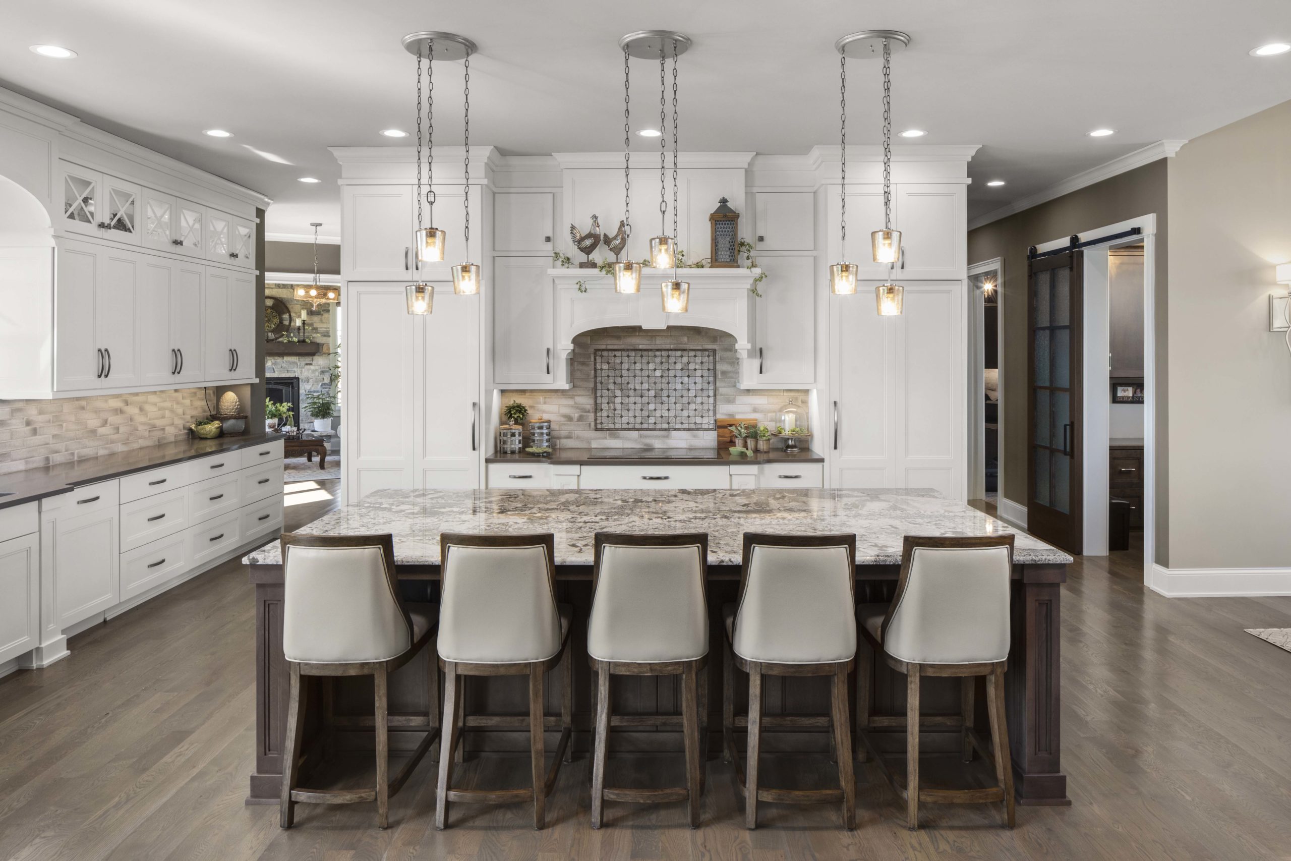 White cabinets in a kitchen with an oversized island and five chairs at the counter
