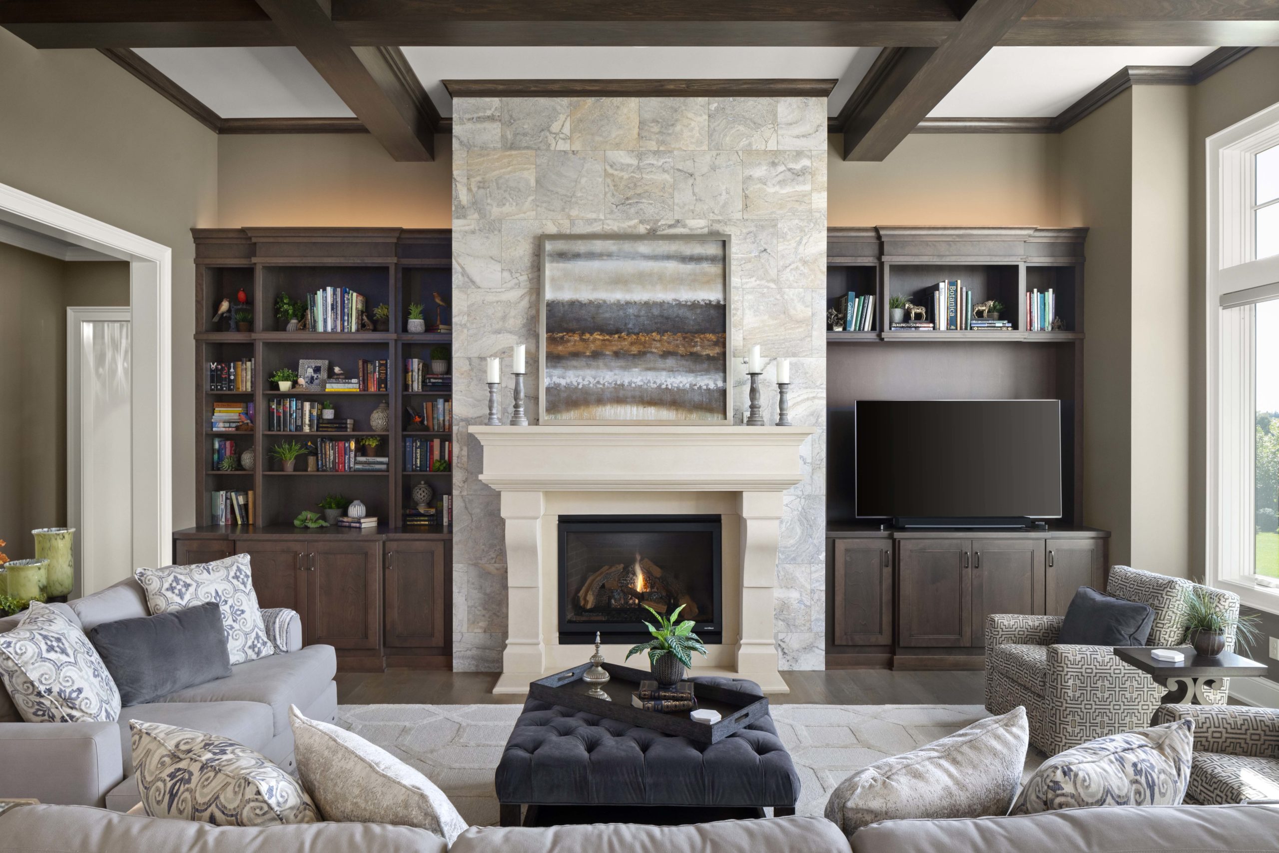 great room with stone fireplace surround, wood ceiling beams, and a sectional sofa