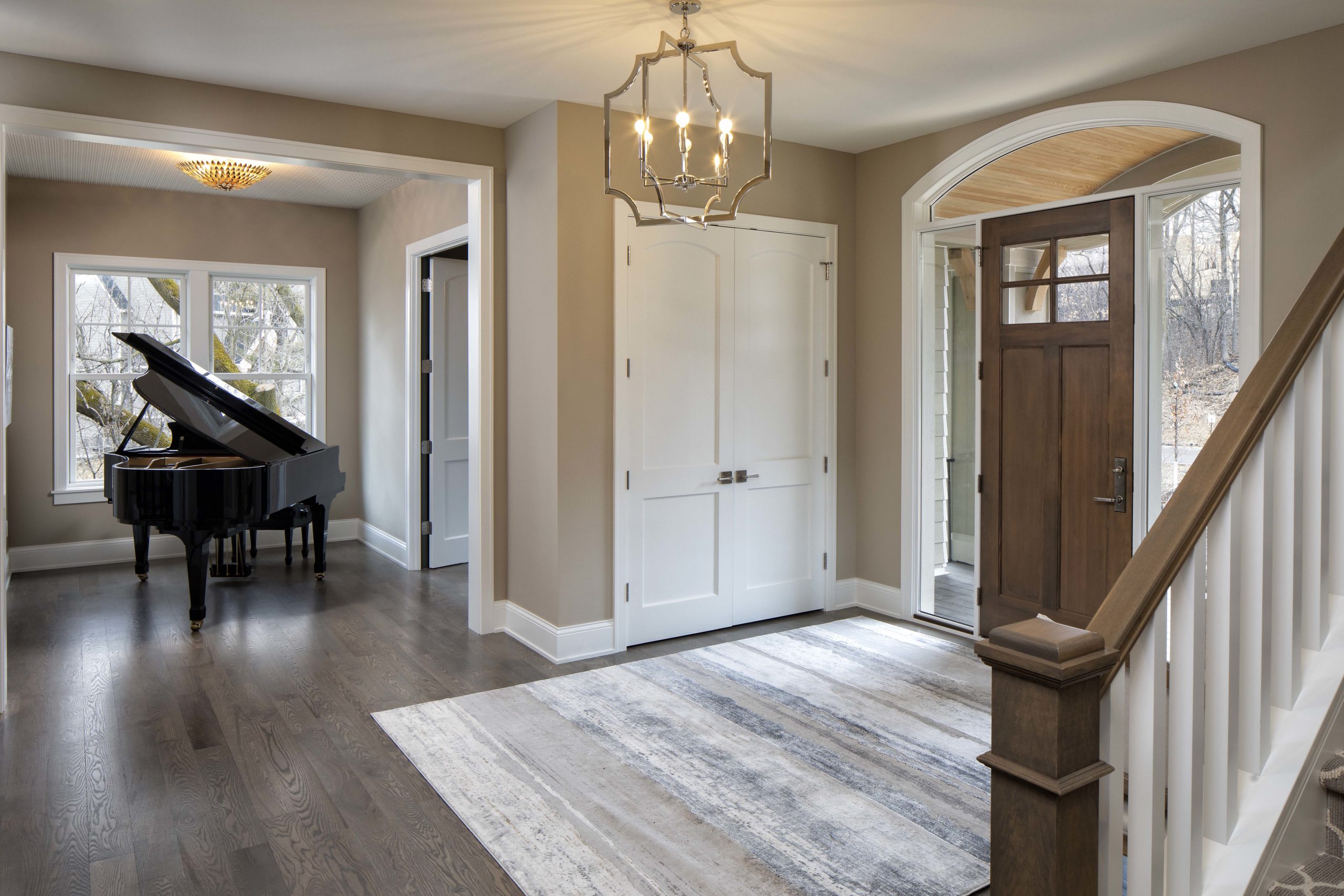 entryway to the home with large wood door and a grand piano