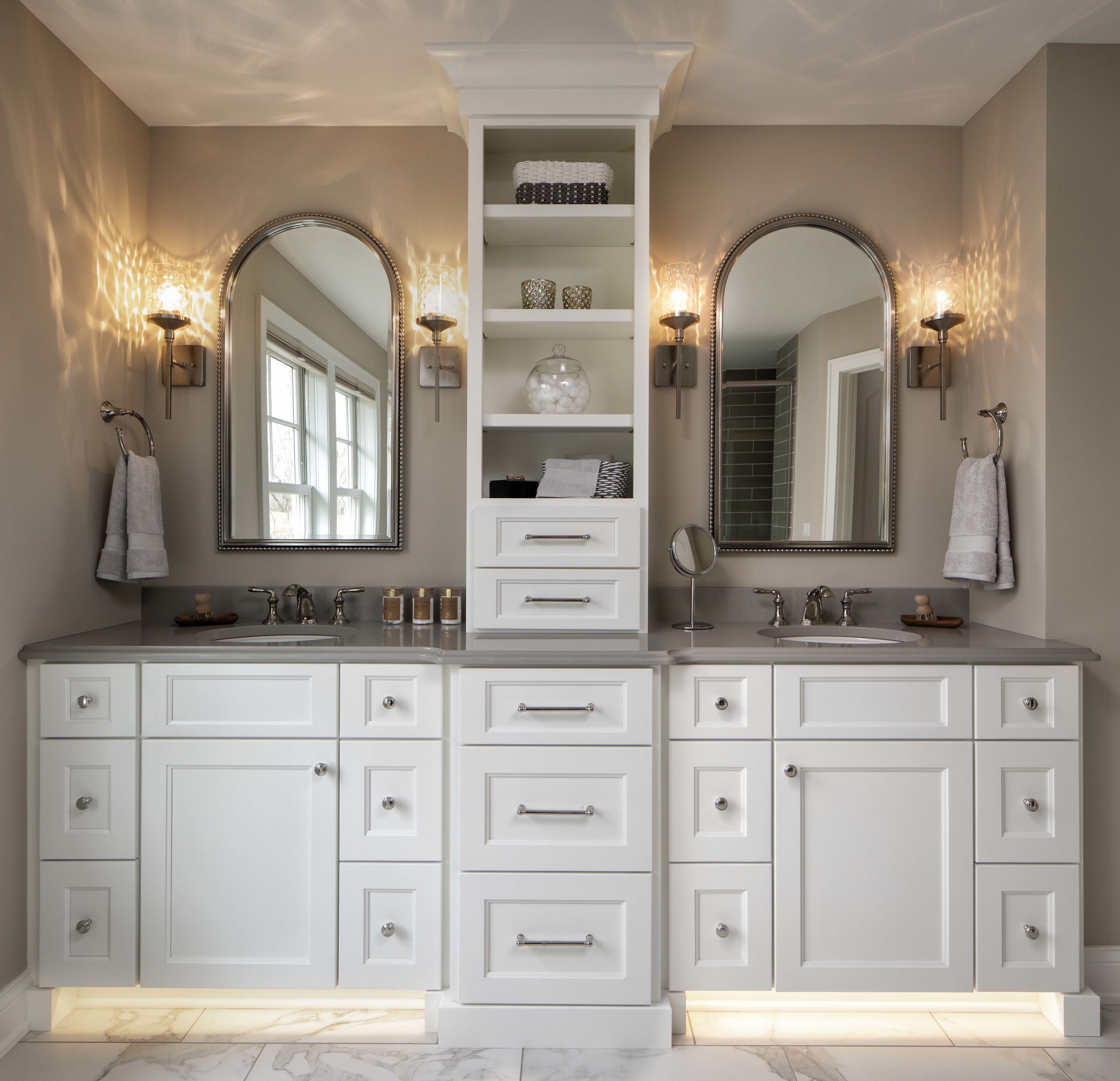 master bathroom with dual white vanities with curved mirrors handing above them