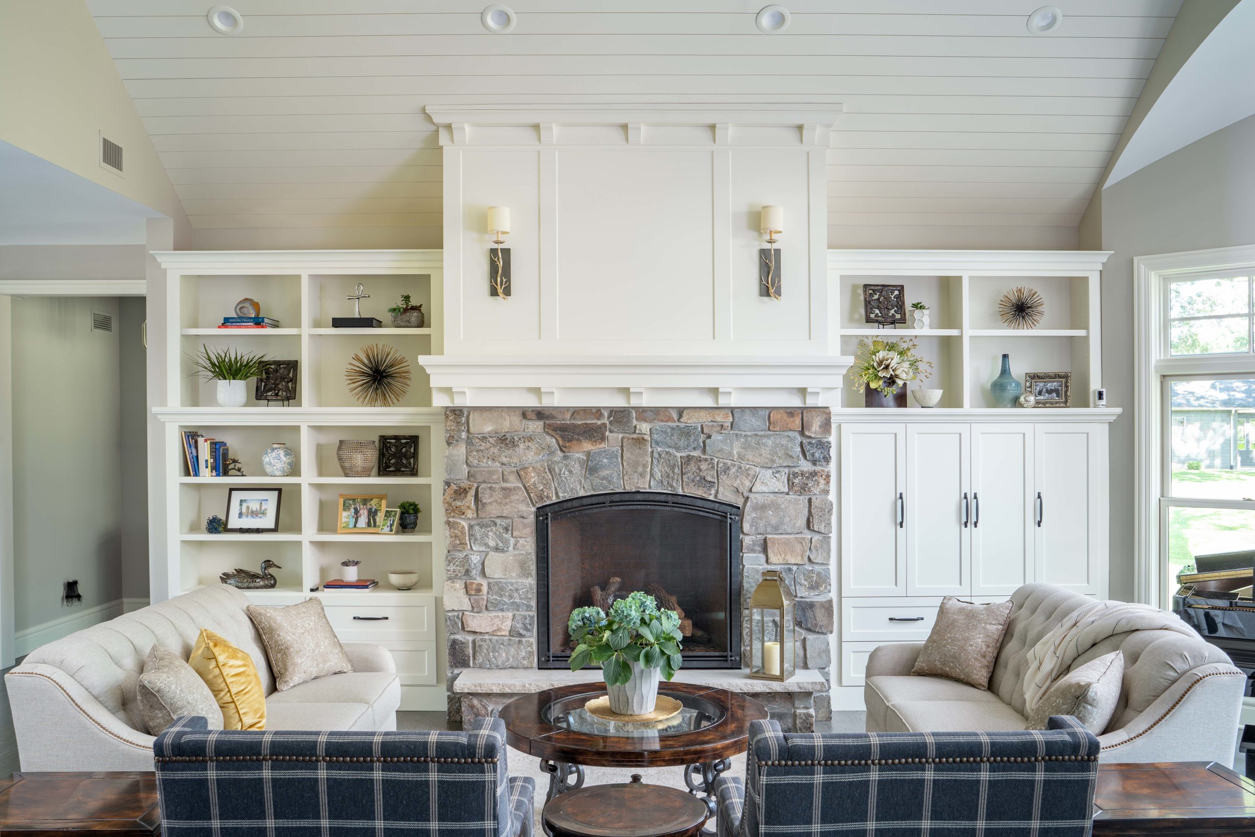 living room fireplace with stone surround and white shiplap ceiling