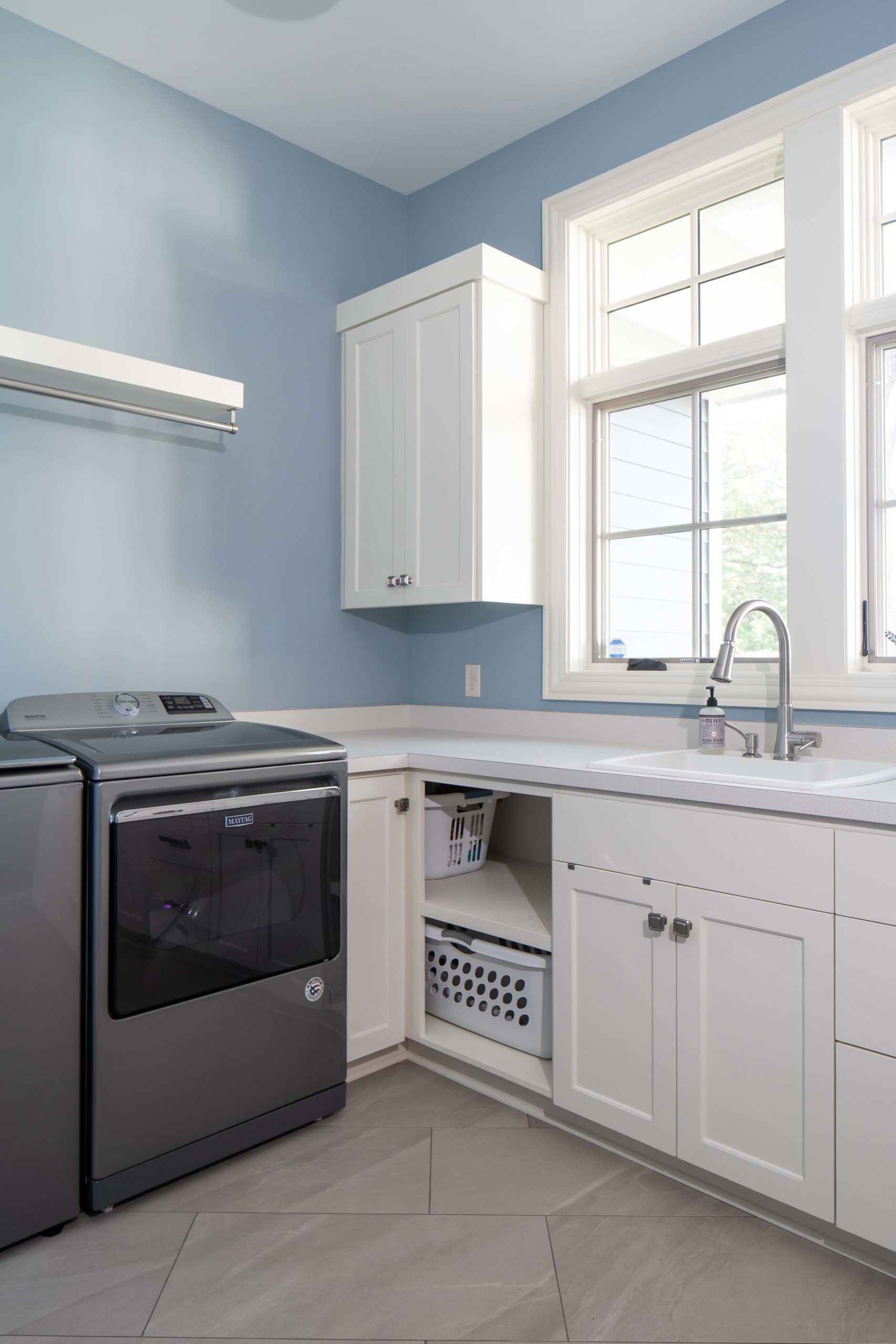 laundry room with white cabinets and blue walls