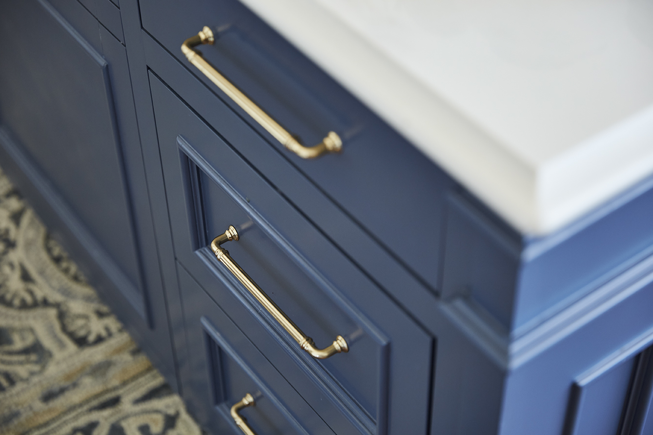 close up image of blue cabinets with gold drawer pulls and white countertops