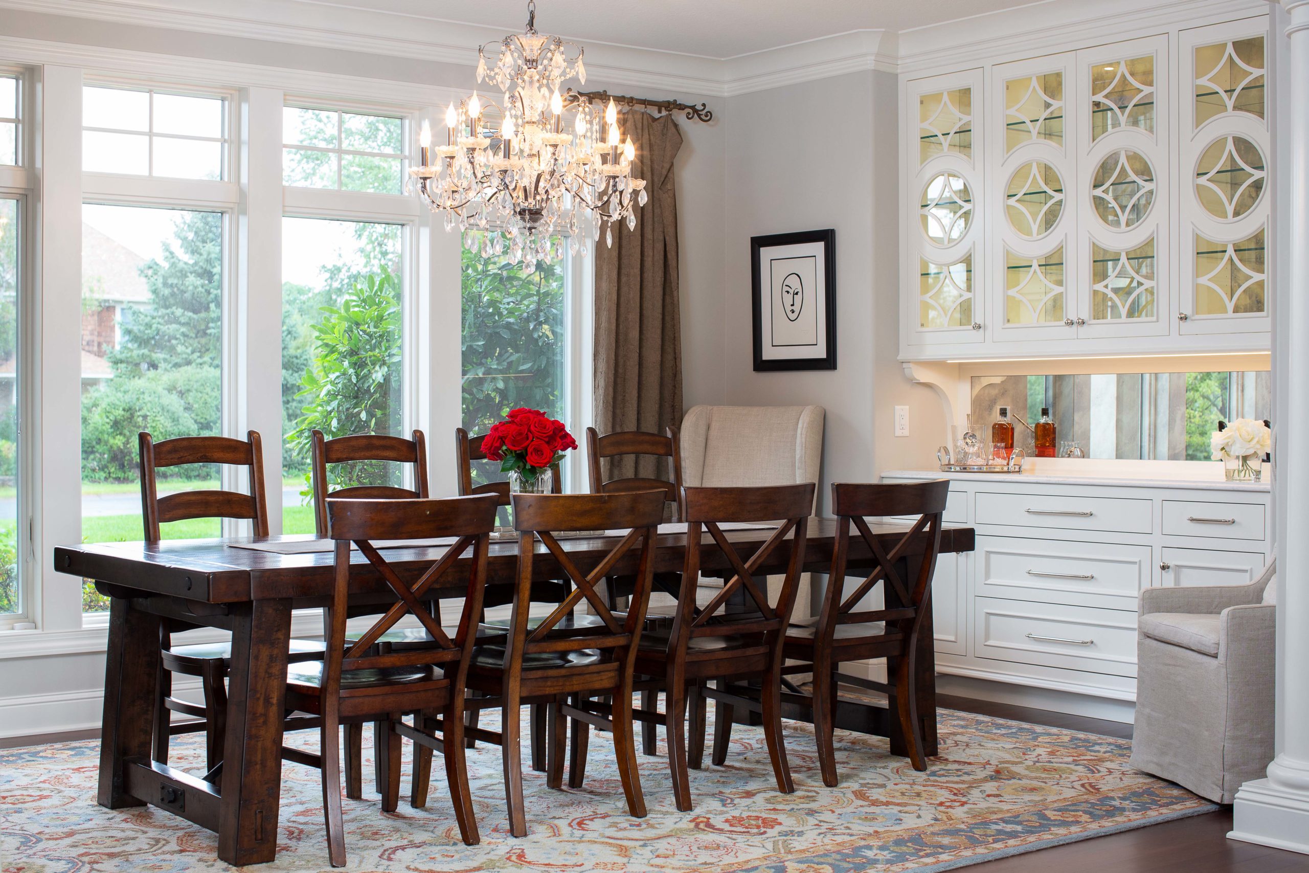 Dining room table with a chandelier hanging above and custom white cabinetry with custom grids