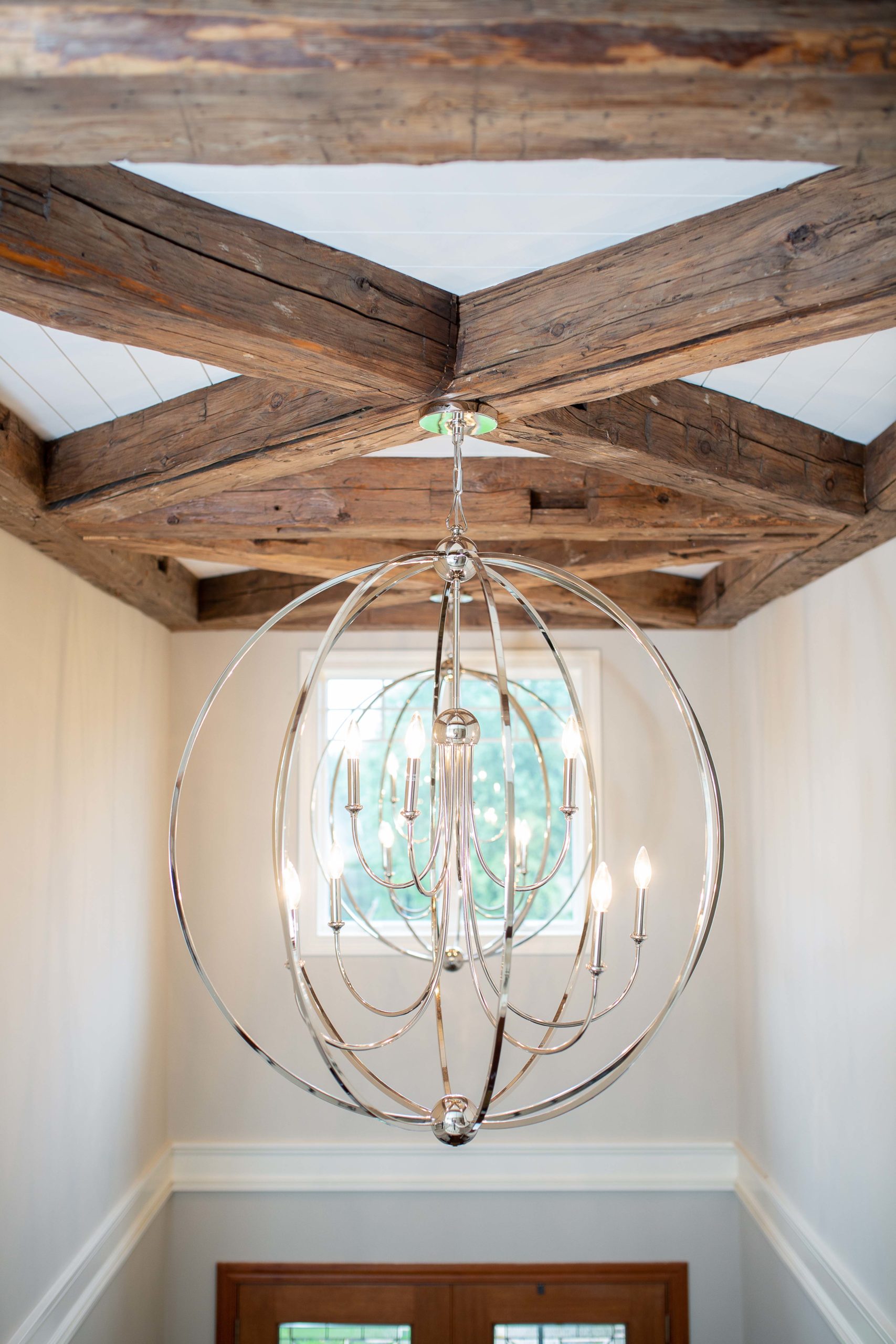 round chandelier light hung from reclaimed wood ceiling beams