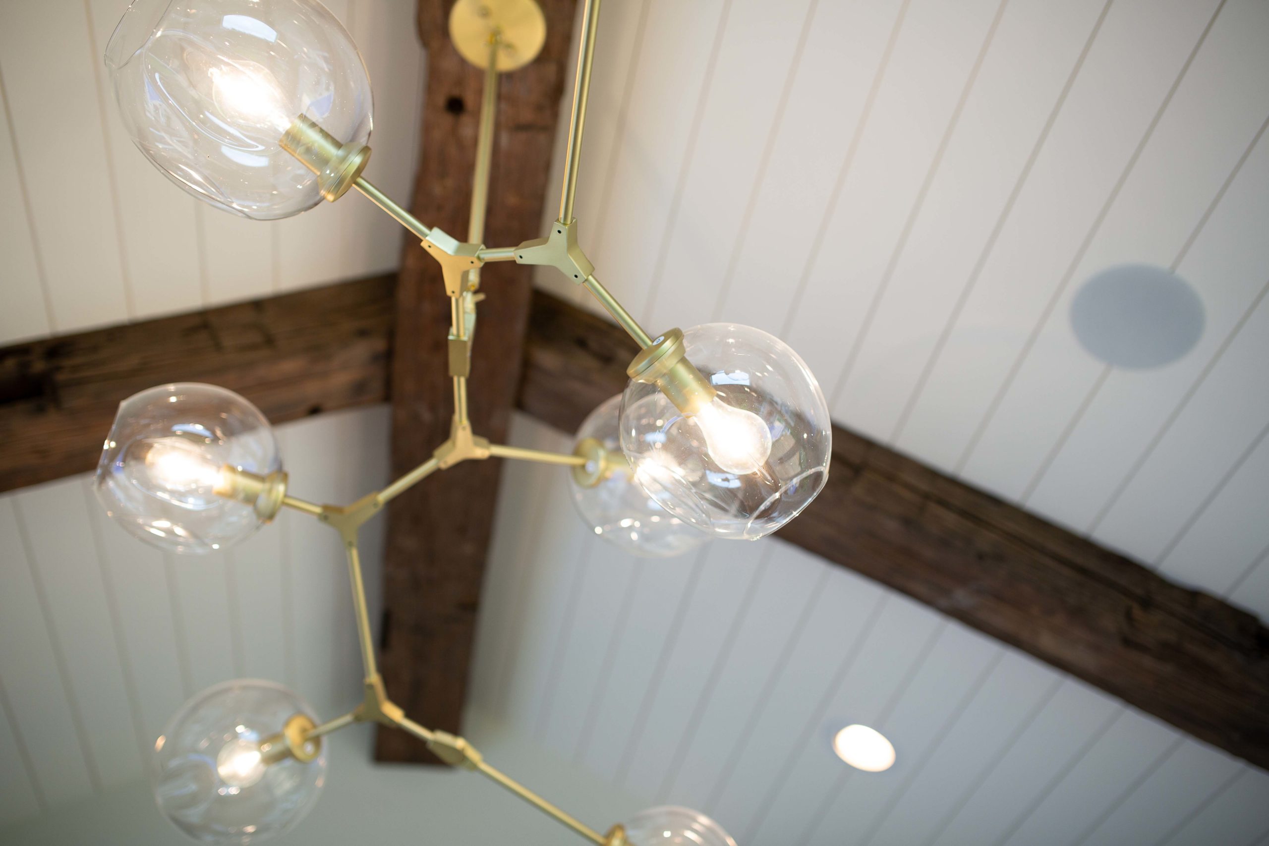 chandelier hung from reclaimed ceiling beams on a shiplap ceiling