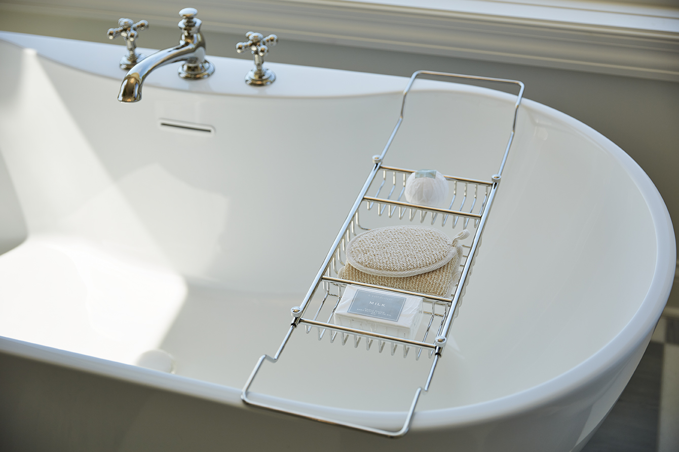 close up of a white soaker tub with soap holder across the top