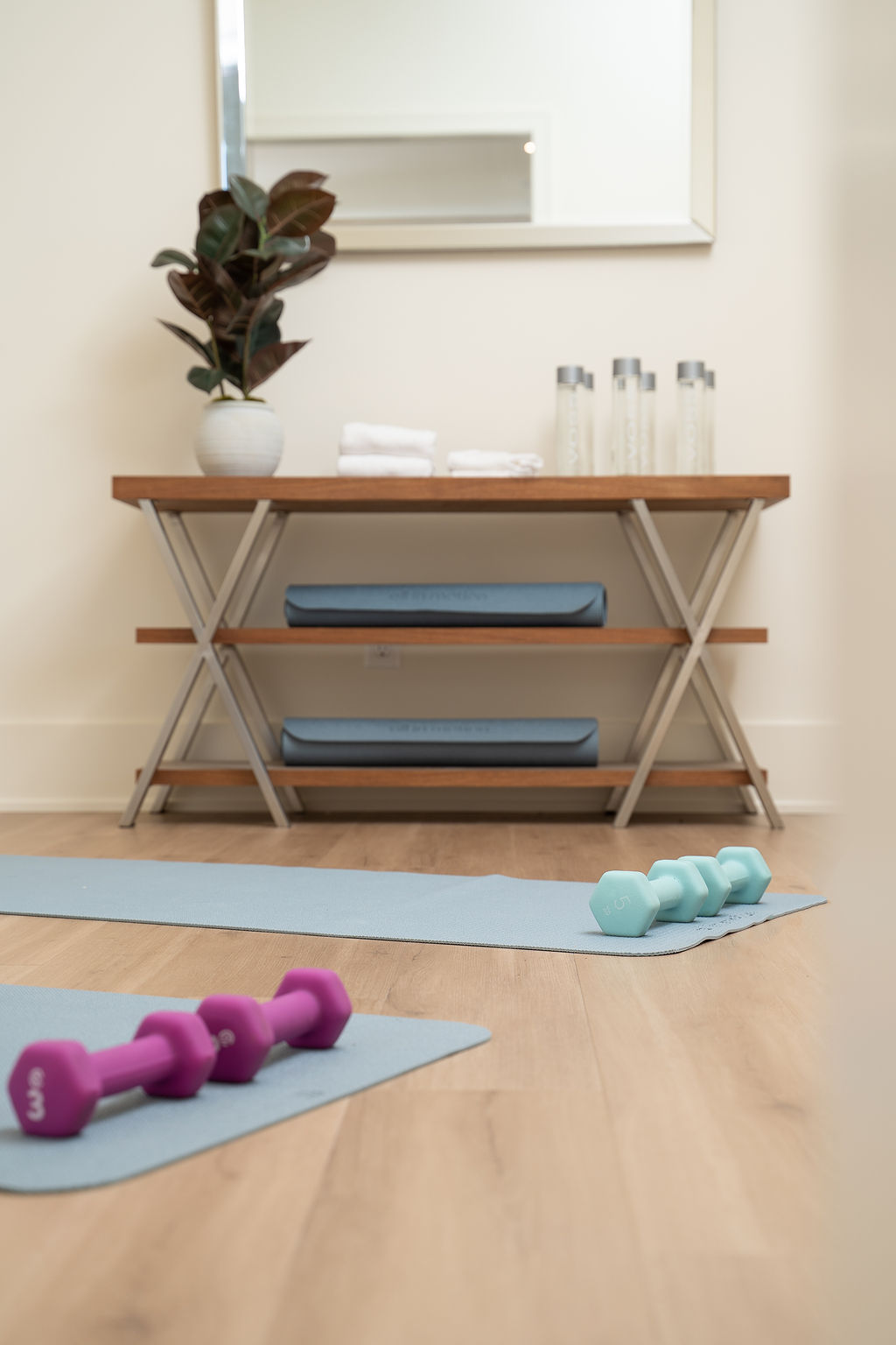 home gym with wood floors, blue yoga mats, and hand weights