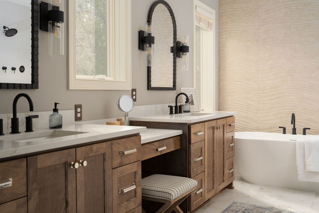 dual vanities in a master bathroom with a bench in the middle