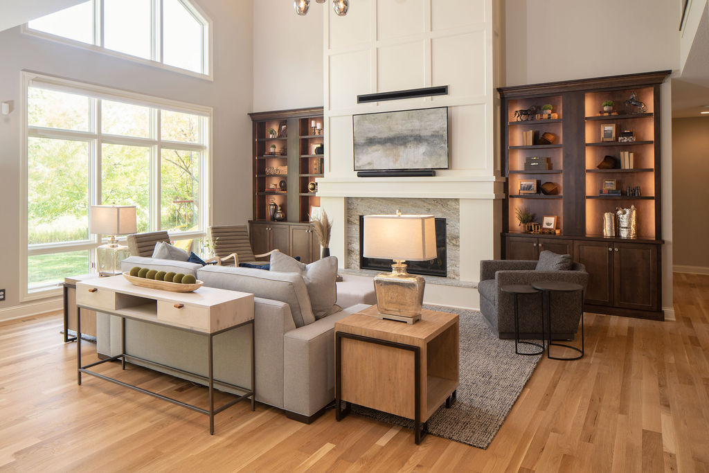 living room with white fireplace surround, wood built in cabinets, and a grey sofa
