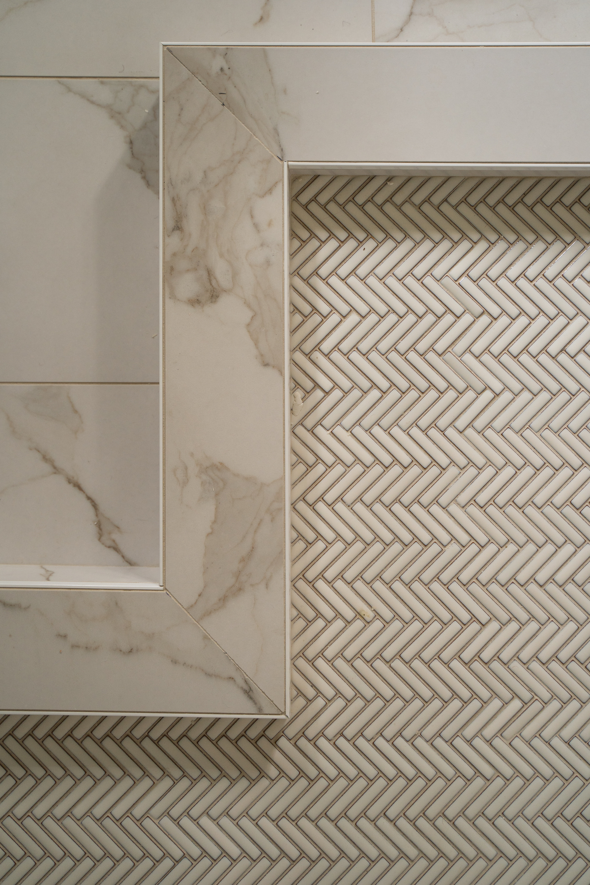 close up image of marbled shower tile next to chevron tile