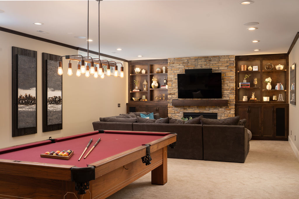 lower level living room with sectional couch and pool table behind it