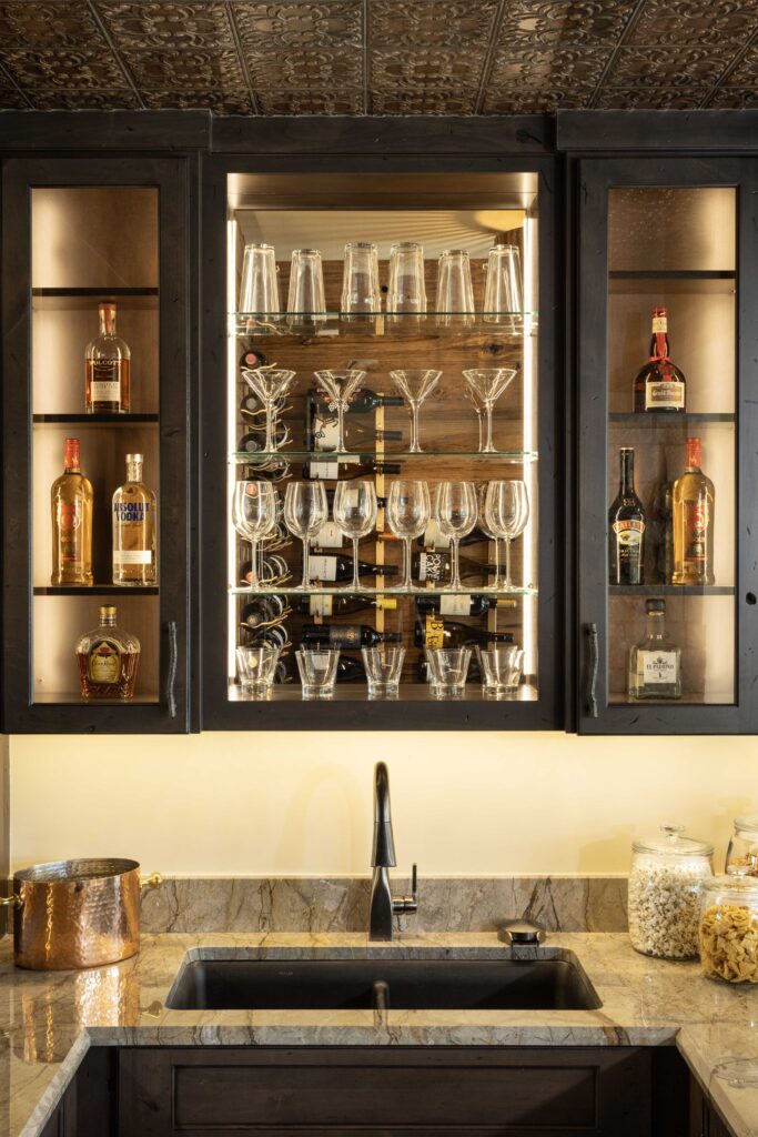 A modern bar with a sink and wine glasses.