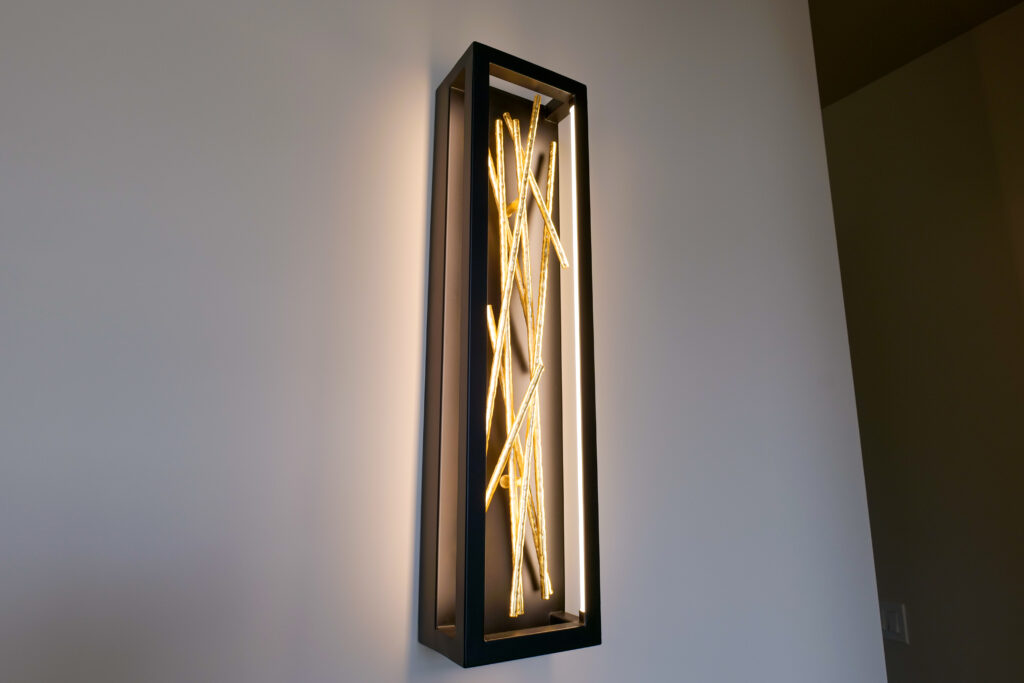 A modern wall sconce with a light on it.