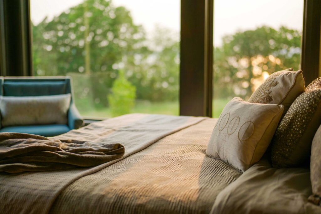 A modern bed with pillows and blankets in front of a window.