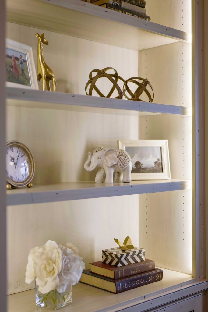 A modern bookcase adorned with a clock and giraffe figurine, along with various other items.