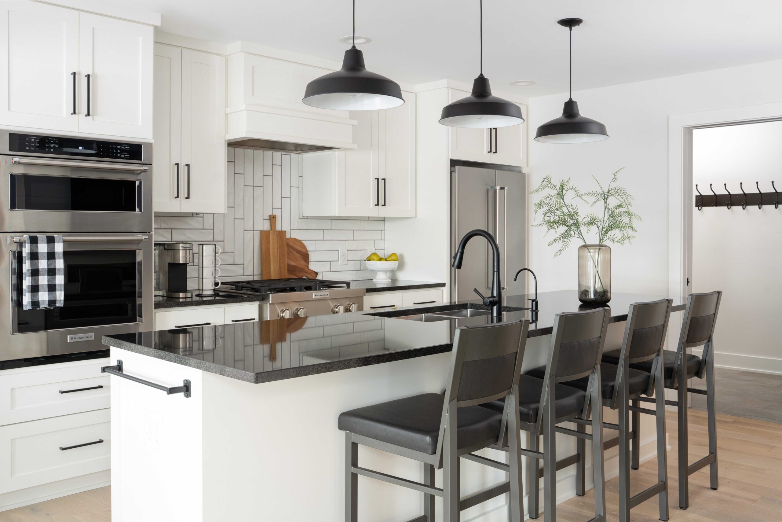 An Orchard Lake remodel with a white kitchen featuring black counter tops and stainless steel appliances.