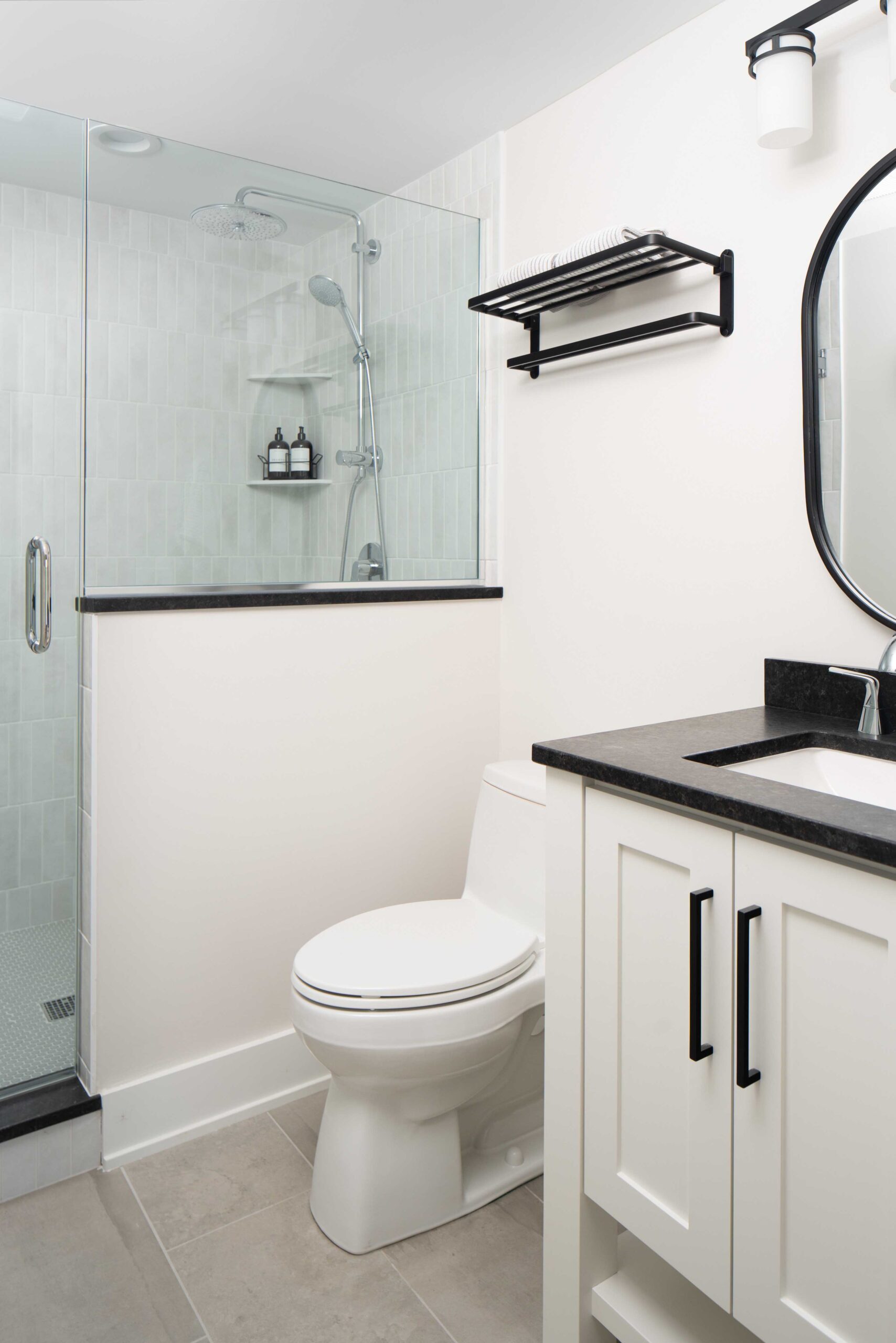 The Orchard Lake remodel features a sleek black and white bathroom with a stunning glass shower stall.