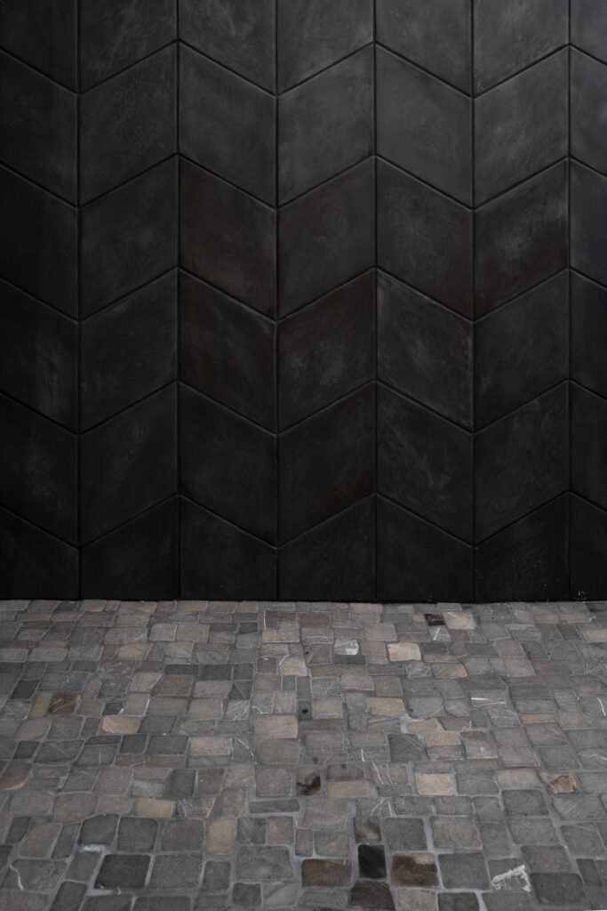 A black tiled wall in a woodside road room.