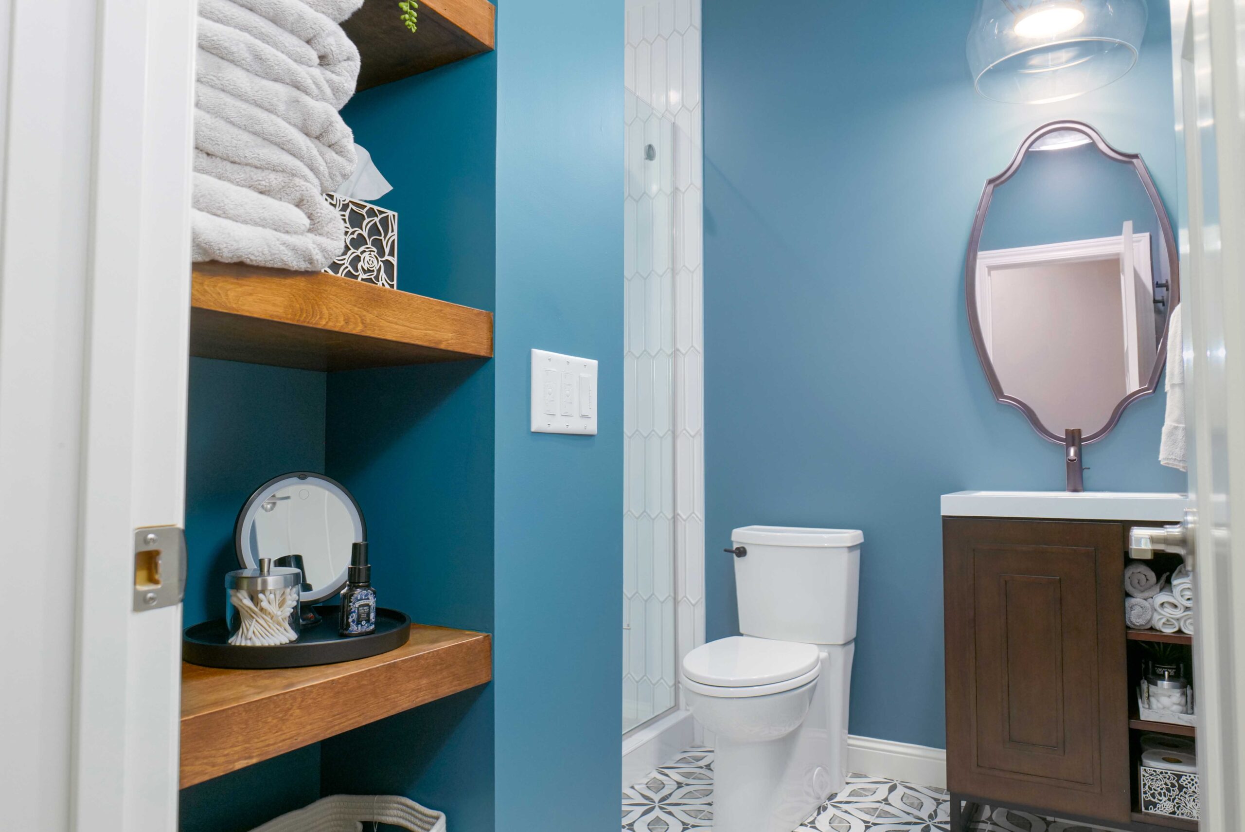 A bathroom with blue walls and wooden shelves, part of the Orchard Lake remodel.