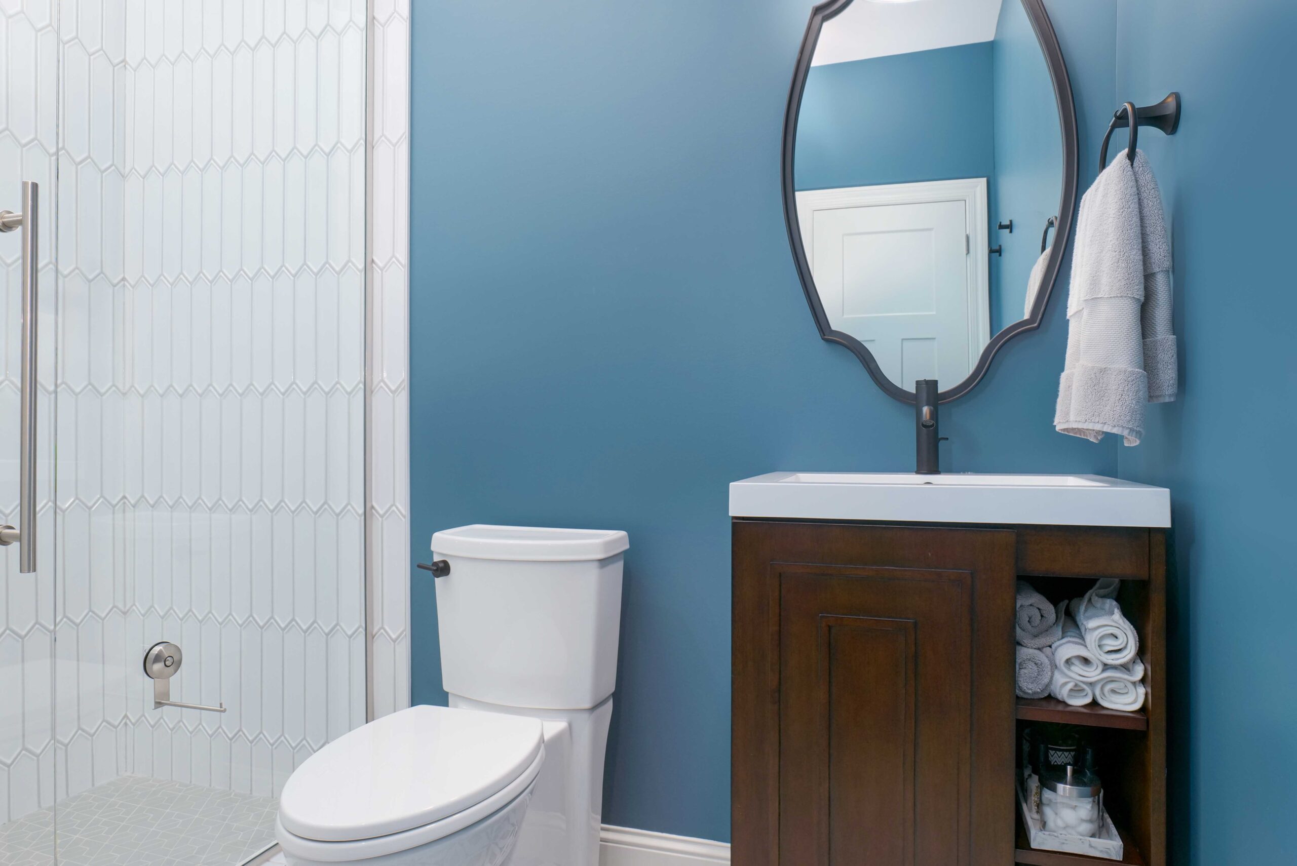 A bathroom with blue walls and a white toilet underwent an Orchard Lake remodel.