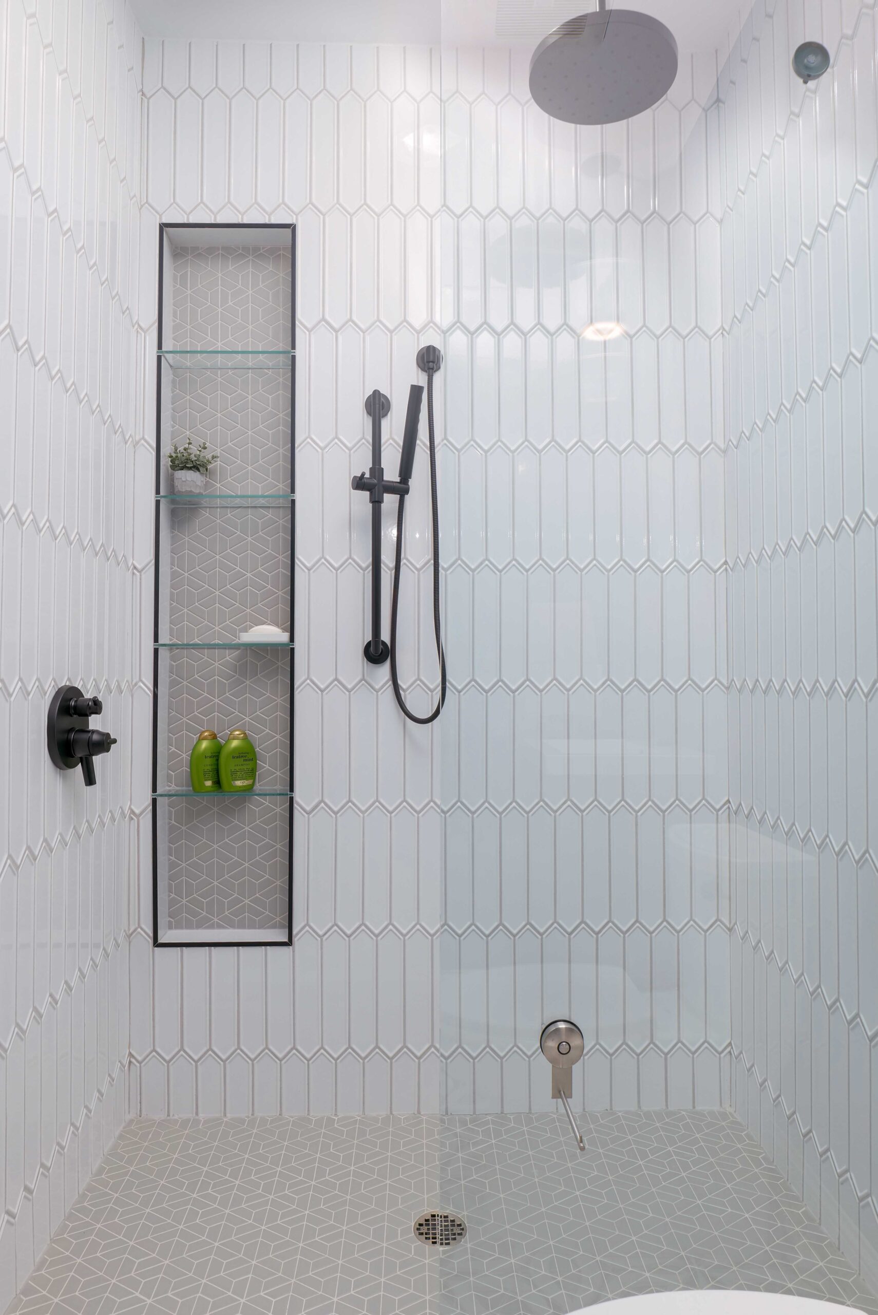 An Orchard Lake remodel featuring a white tiled shower with a glass shower door.