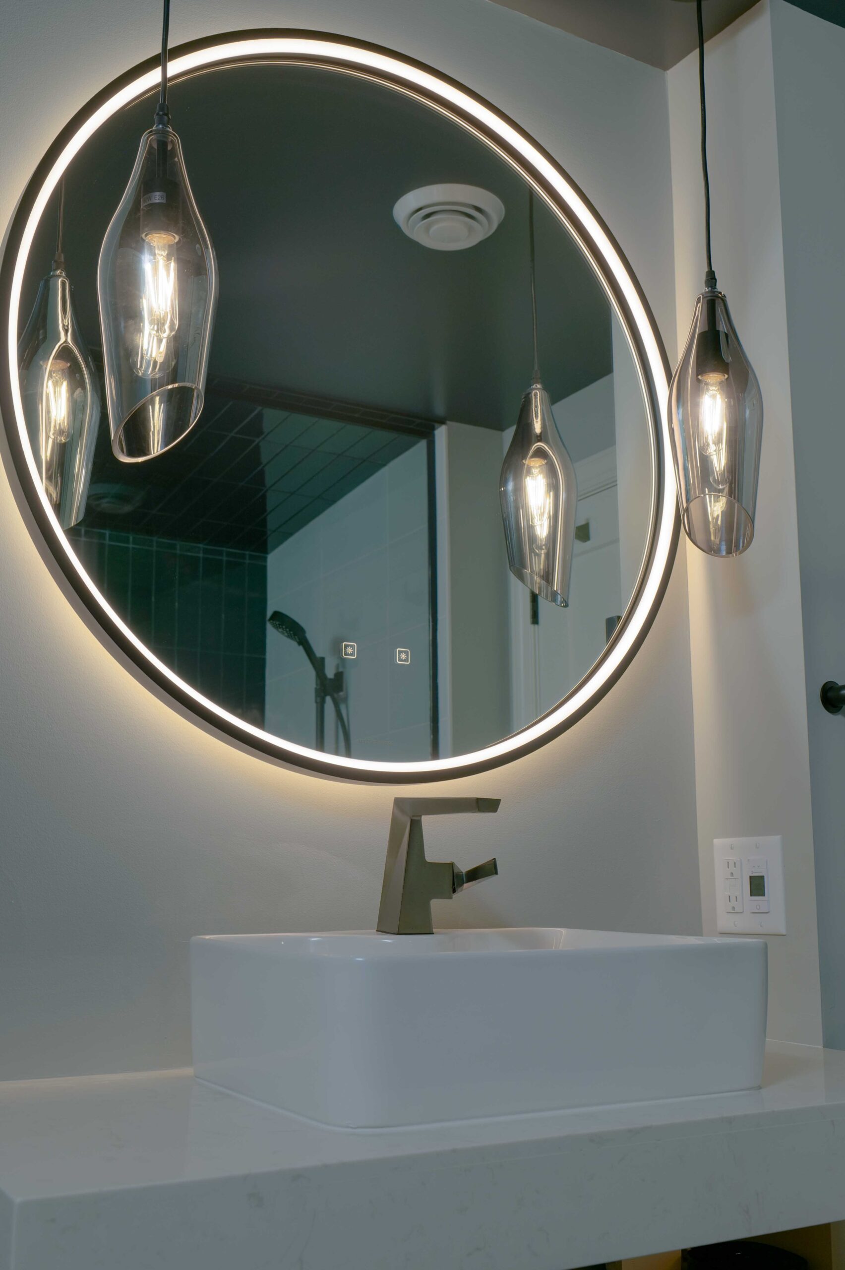 An Orchard Lake remodel with a bathroom featuring a round mirror and lights above it.